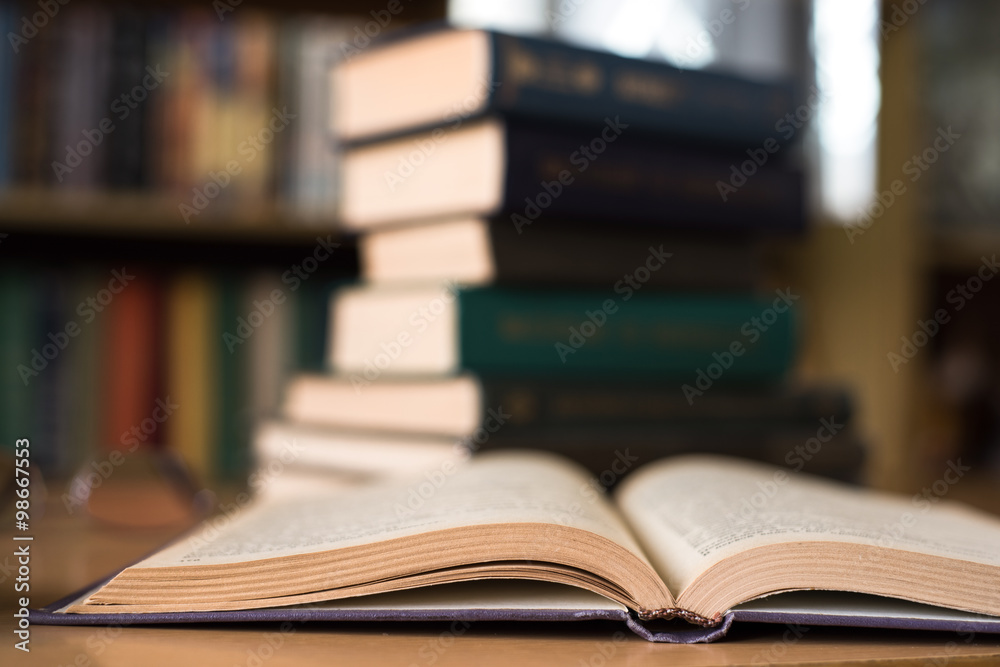 Opened Book and a Stack of Books on the Background Opened Book and a Stack of Books on the Background