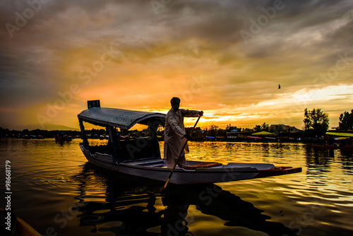 The silhouette of a boat glides along the surface of Dal Lake du