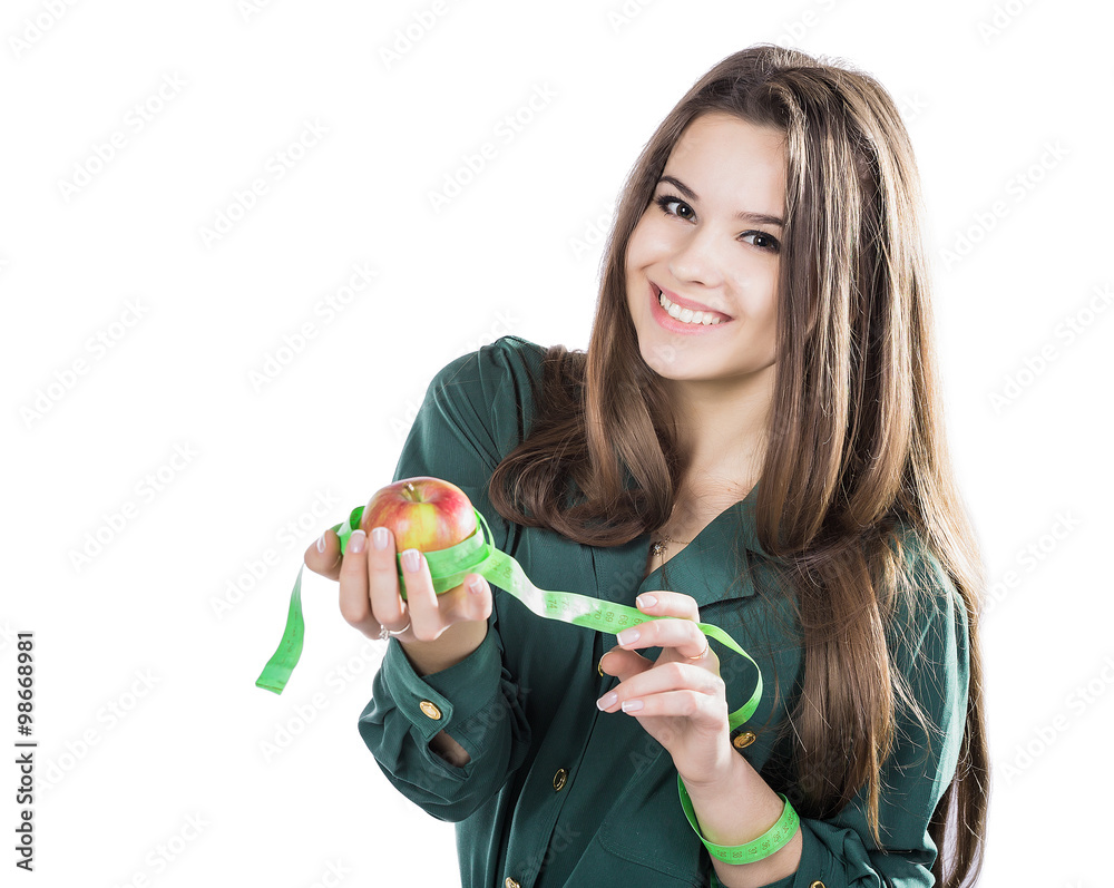 young beautiful girl with dark hair isolated on a white background holding an apple with a tape measure.Smile young beautiful girl with dark hair isolated on a white background holding an apple with a tape measure.Smile