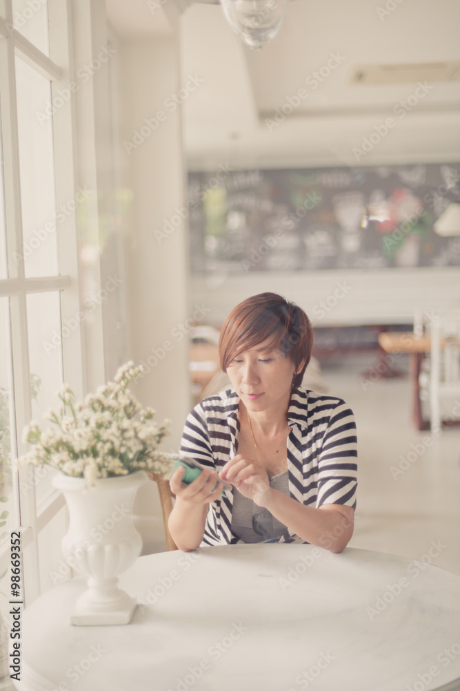 Smart Asian woman using smartphone in coffee shop. Smart Asian woman using smartphone in coffee shop.
