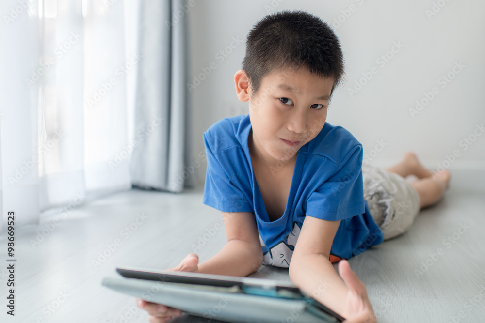 Boy using digital tablet while lying on floor at home Boy using digital tablet while lying on floor at home