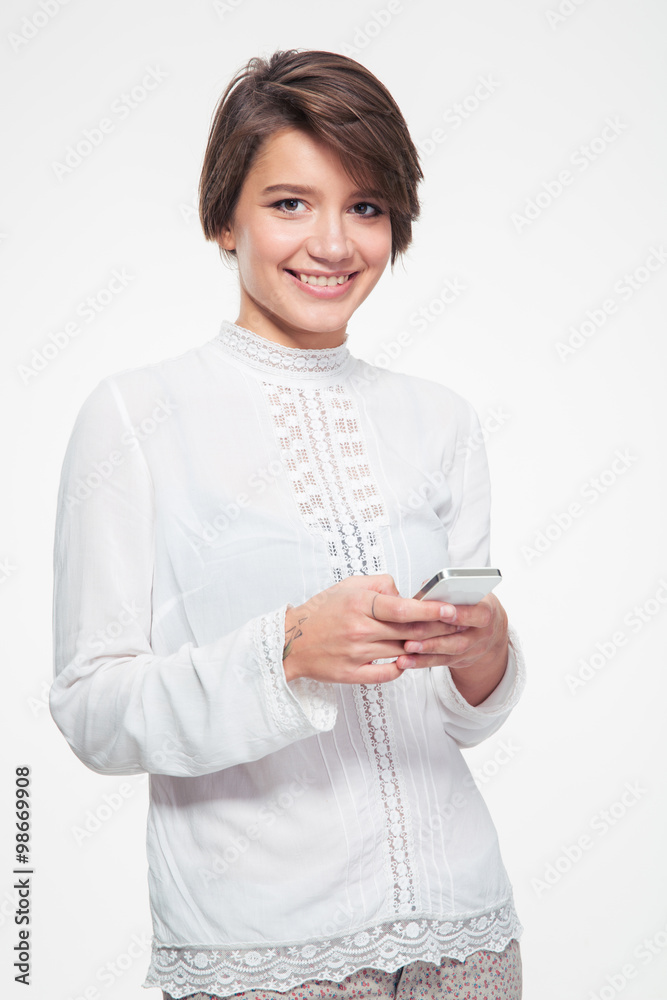 Smiling attractive young woman standing and using mobile phone Smiling attractive young woman standing and using mobile phone