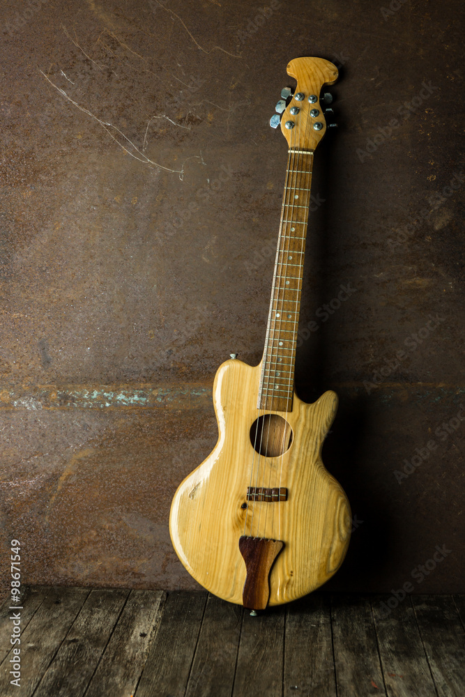 Naklejka premium Acoustic guitar resting against an old steel background