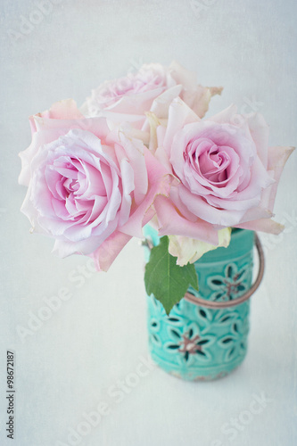 Beautiful pink roses in a blue ceramic vase on a light background. 