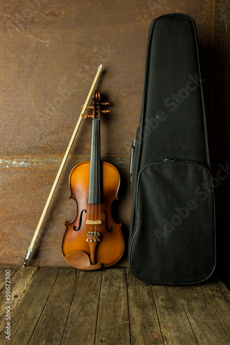 vintage violin resting against an old steel background © ittipol