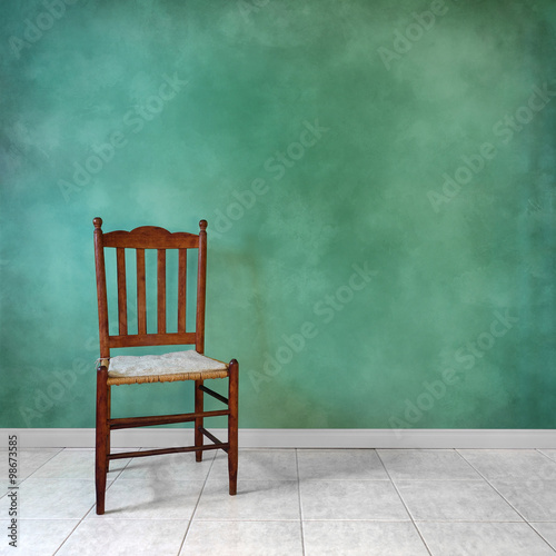 Antique oak chair in front of a green wall