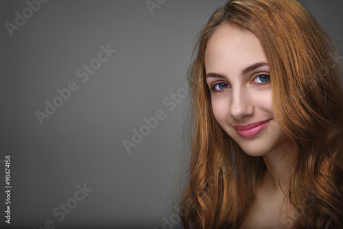 Portrait of beautiful young woman isolated on gray.