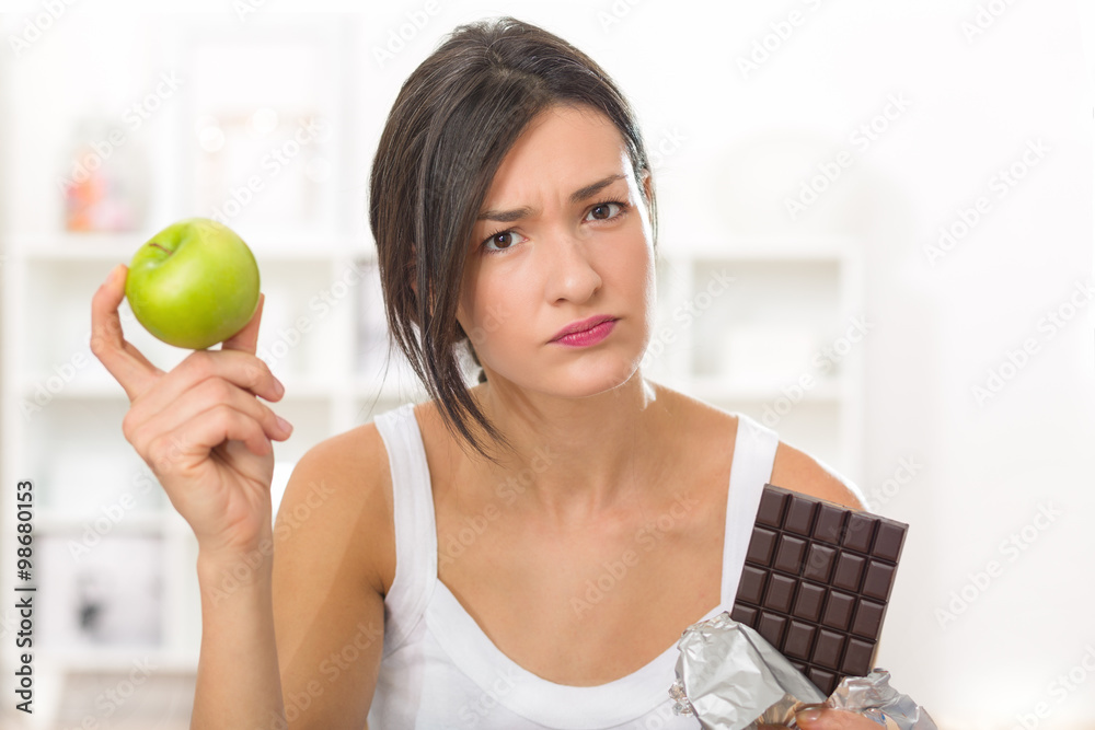 Girl tempted to eat a chocolate instead of an apple after work out Girl tempted to eat a chocolate instead of an apple after work out