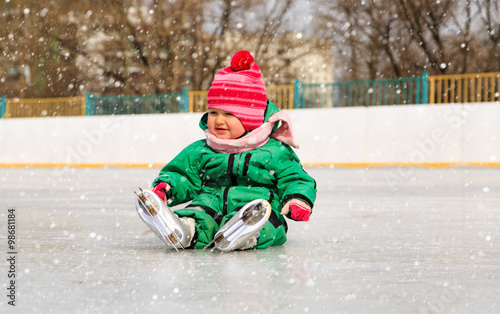 cute little girl sitting on ice with skates