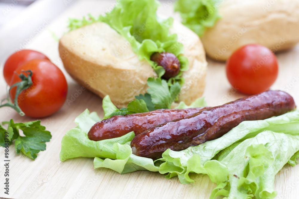 Hot dog. Grilled hot dogs with fresh salad lettuce on wooden table. Hot dog. Grilled hot dogs with fresh salad lettuce on wooden table.