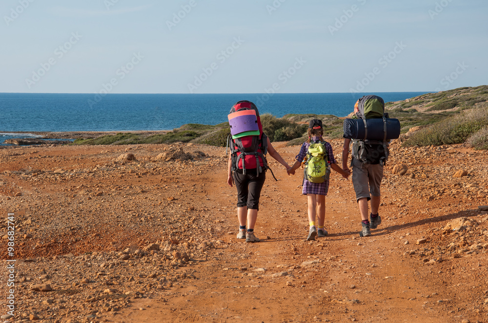 family with large backpacks are on road sea