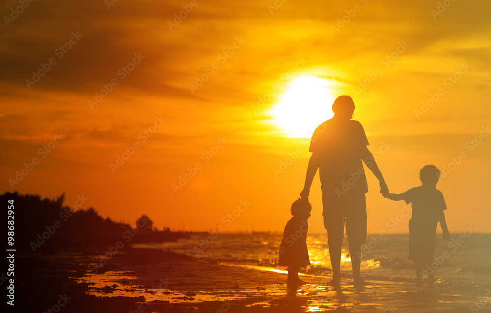Fototapeta premium father and two kids walking at sunset