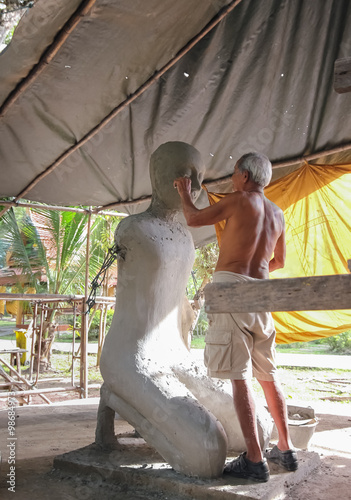 Elderly artist sculptor making monk sculpture at the temple