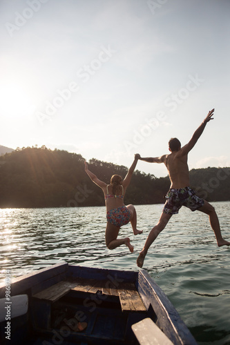 Young couple jumping on the edge of a boat