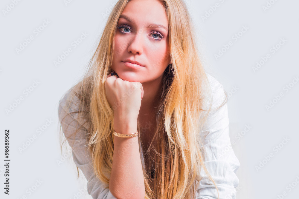 Young beautiful girl in shirt, sitting, leaning on arm and looking to camera, beauty concept, isolated Young beautiful girl in shirt, sitting, leaning on arm and looking to camera, beauty concept, isolated