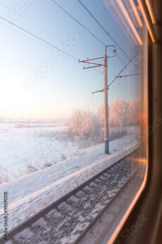 frozen pink sunrise in winter forest through the window of the train