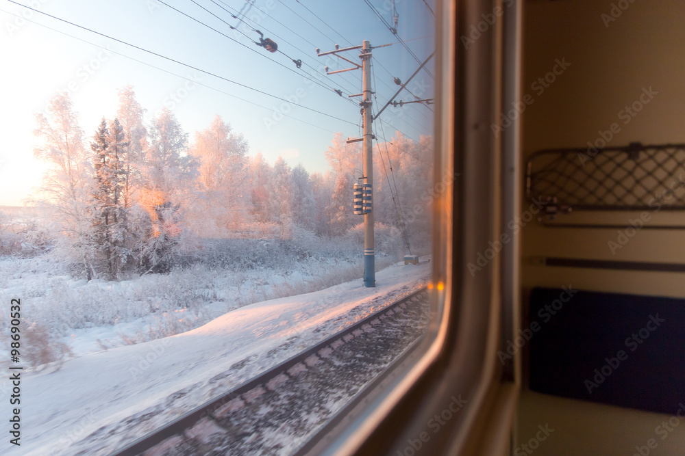 Naklejka premium pink sunrise in winter forest through the window of the train