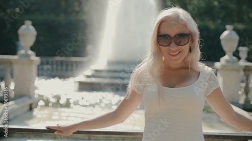 Happy blonde woman walking near the fountain