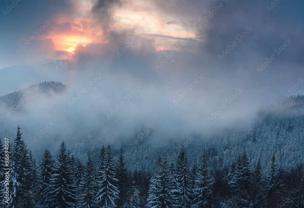 Colorful winter evening in the mountains at sunset. Dramatic overcast sky.