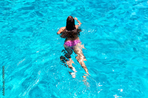 Young woman swimming in clear ocean water.