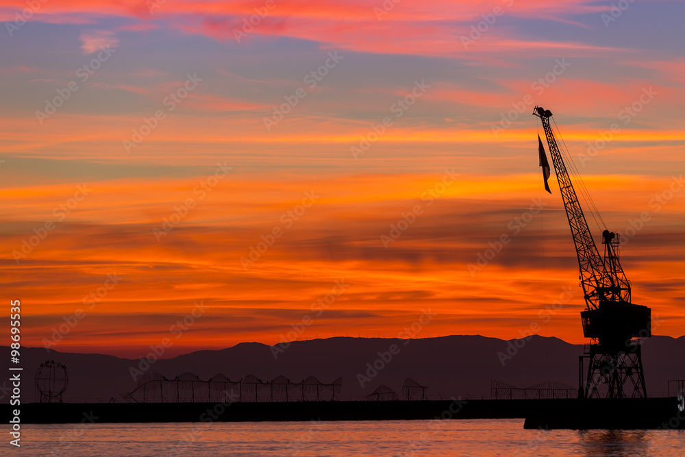 Silhouette of a drilling rig against dramatic sunset
