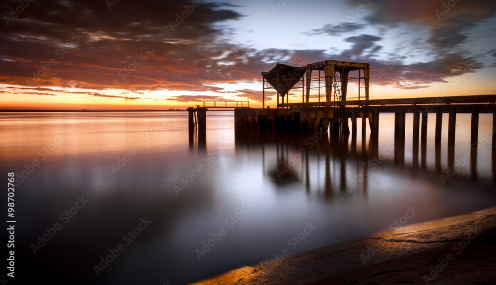 Ancient industrial pier over a sunrise