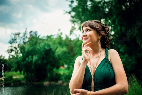 фотографія Portrait of a young attractive girl in green dress with deep decollete  in the p