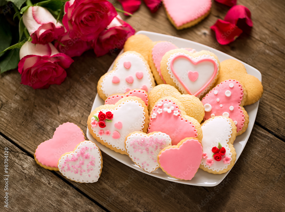 Beautiful tasty valentine day cookies on plate and roses Beautiful tasty valentine day cookies on plate and roses