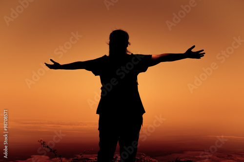 Silhouette back view of woman open arms under the sunrise. © kdshutterman