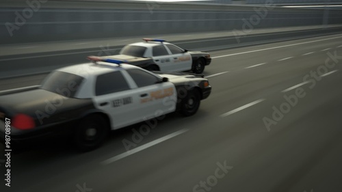 Two police cars chase. The vehicles are involved in the urgent pursuit.
