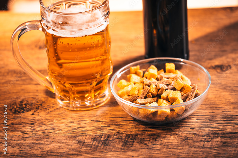 glass of fresh bright beer and crackers on wooden table glass of fresh bright beer and crackers on wooden table