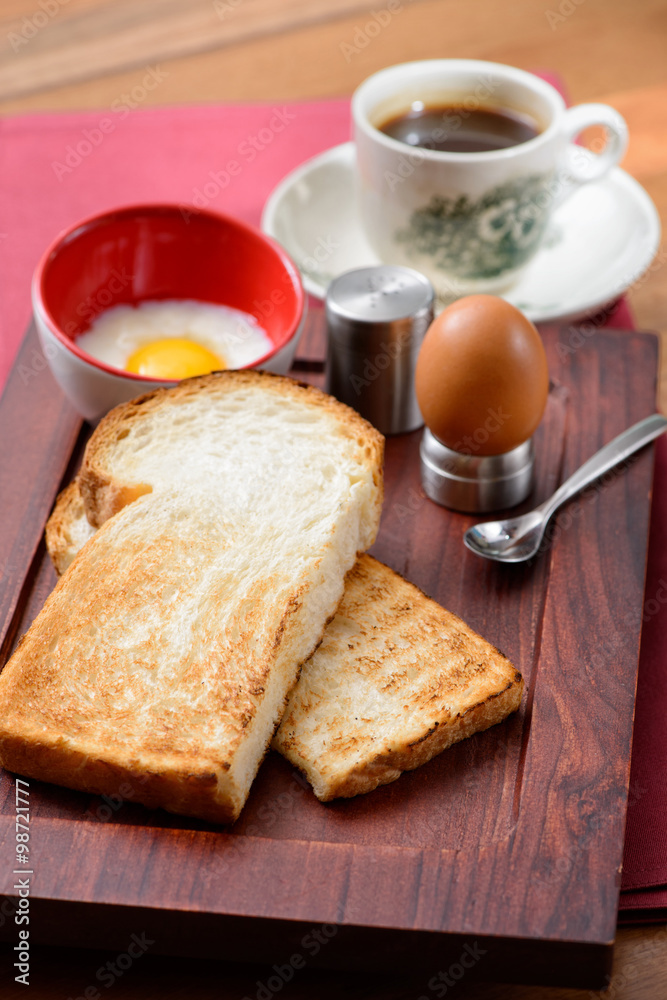 Breakfast set in consisting of coffee, toast bread and half-boiled egg