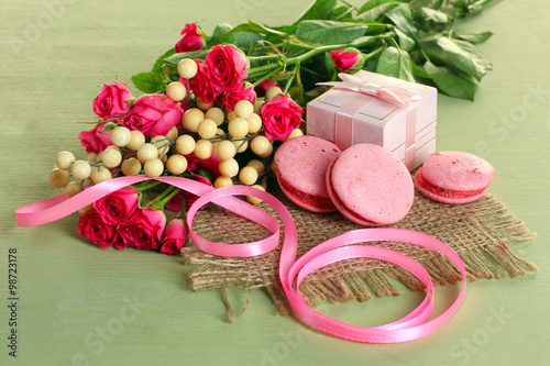 a bouquet of roses with ribbon and sweets near the gift boxes on cloth on a wooden green table