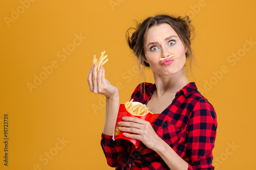 Fotografie Funny pretty young woman making fake moustache with fries