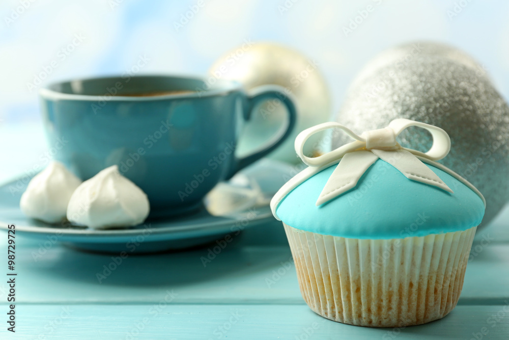 Tasty cupcake with bow, coffee cup and Christmas toys on color wooden background Tasty cupcake with bow, coffee cup and Christmas toys on color wooden background