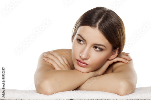 Portrait of a serious young woman is lying down on towel