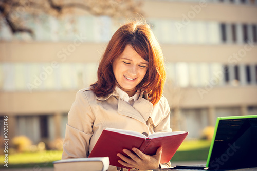 Happy student girl in campus holding a red journal . Young Businesswoman,Life style. Student girl learning preparing for an exam in campus.