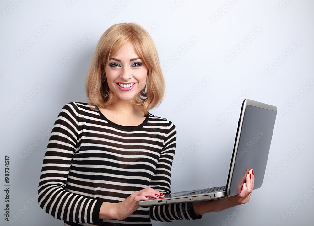 Happy blond casual woman holding laptop in hand and toothy smili Happy blond casual woman holding laptop in hand and toothy smili