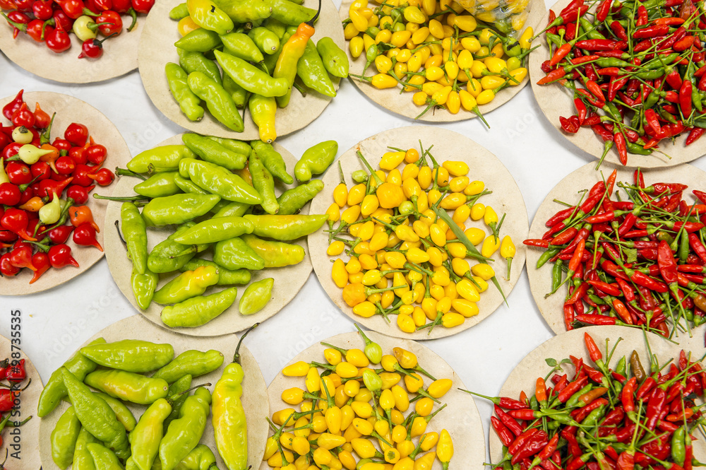 Colorful hot peppers in bright red, yellow, and green piles at farmers ...