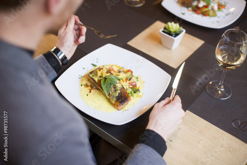 Man eating grilled salmon a...