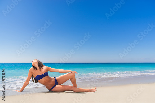 beautiful young girl pointing to the sea on tropical beach
