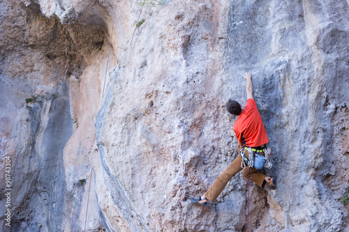 Fototapeta Naklejka Na Ścianę i Meble -  Young male climber hanging by a cliff.