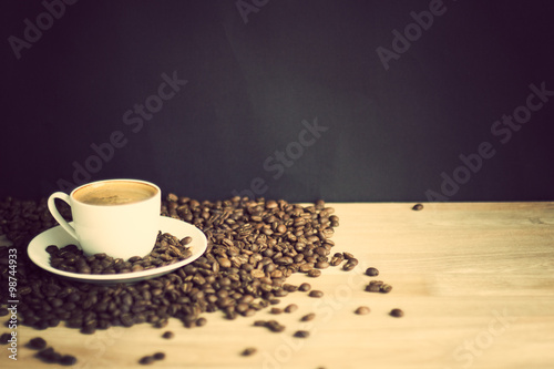 Coffee cup and coffee beans over wood