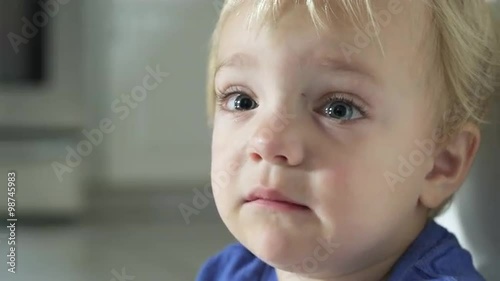 A tearful little boy looks into the camera and weeps.