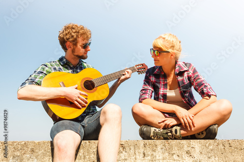 Young man hipster playing guitar for woman.