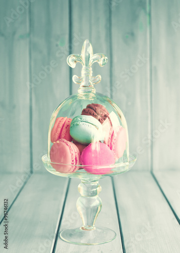 Colorful macaroons in a glass vase over turquoise wood