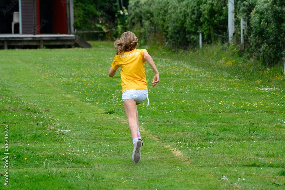 Young girl runs on a green field