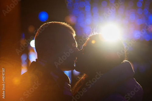 Happy couple kissing on the background of illuminations and bokeh