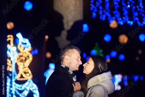 Happy couple kissing on the background of illuminations and bokeh