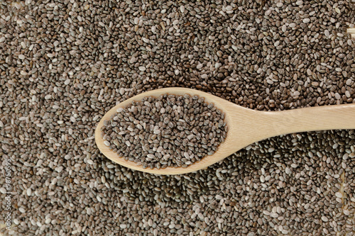 Handful of chia seeds on wood spoon and background